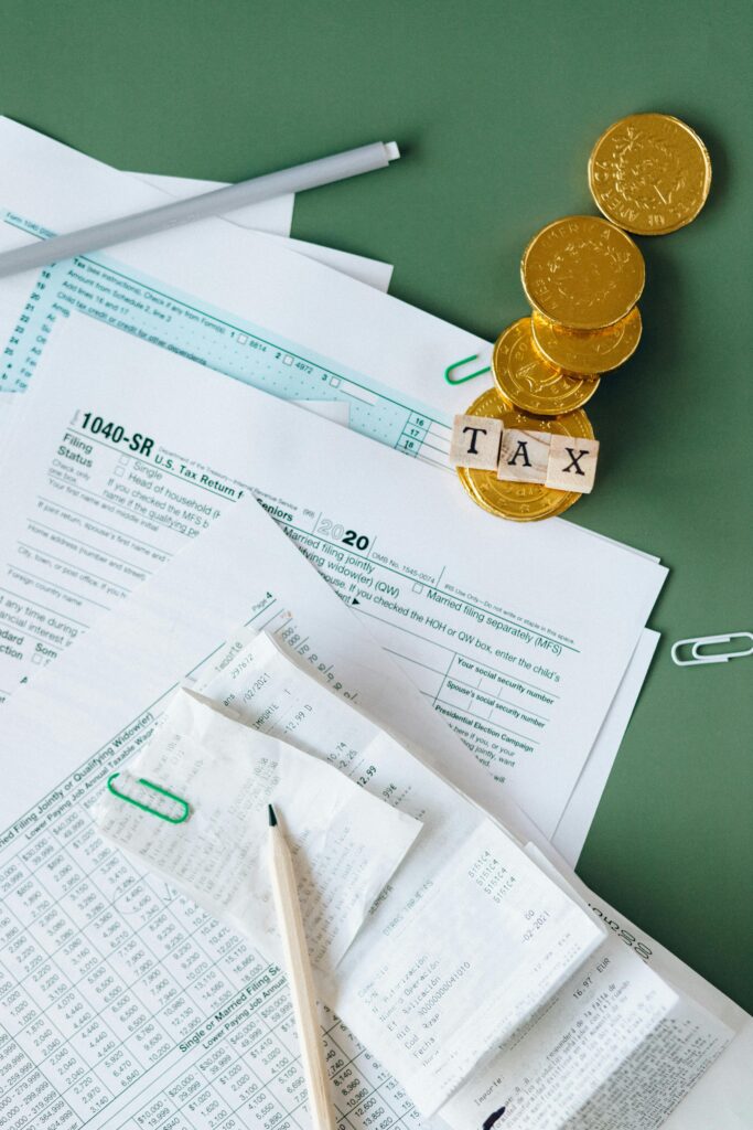 pexels-photo-6863182-6863182 Tax documents and gold coins on a green desk symbolizing financial planning and savings.