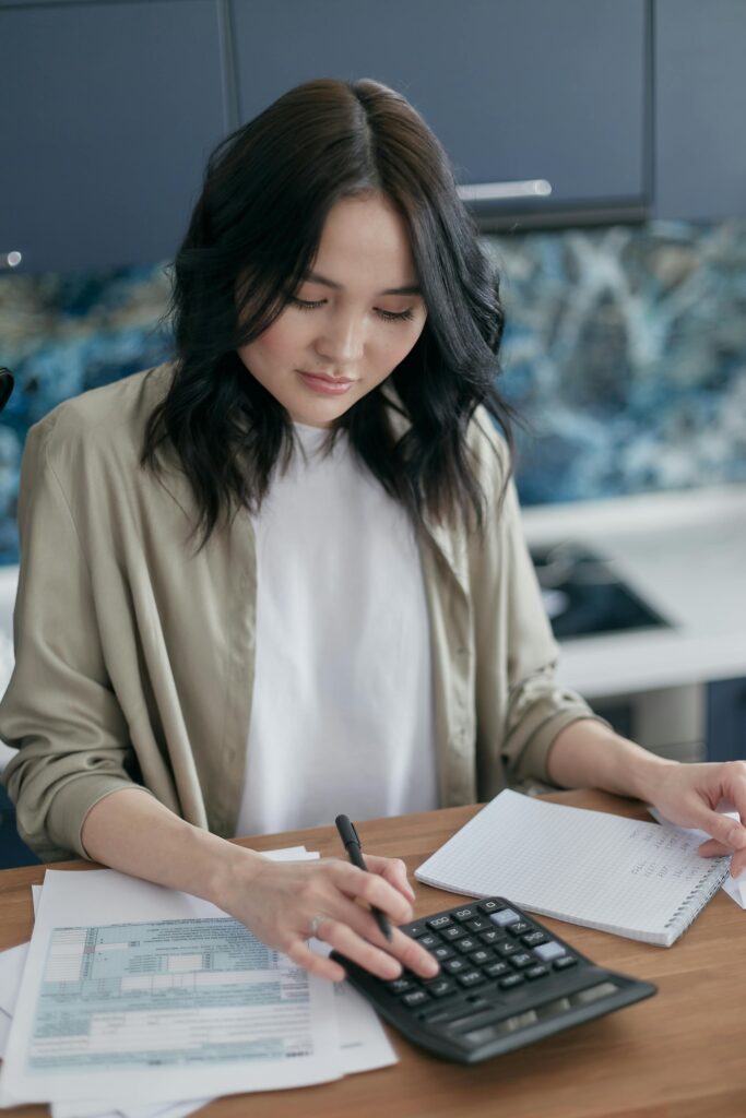 pexels-photo-6962992-6962992 Woman using a calculator for budgeting and finance management at home desk.